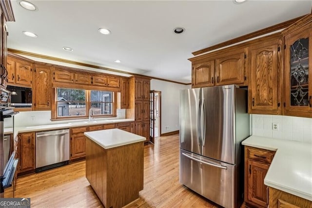 kitchen featuring sink, light hardwood / wood-style flooring, backsplash, stainless steel appliances, and a center island