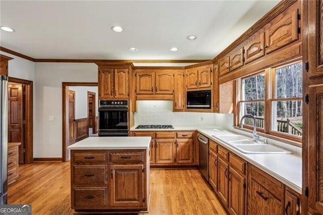 kitchen with tasteful backsplash, sink, ornamental molding, black appliances, and light hardwood / wood-style flooring