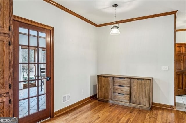 doorway to outside with ornamental molding and light hardwood / wood-style flooring