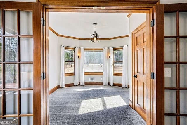 doorway to outside featuring crown molding, carpet, and plenty of natural light