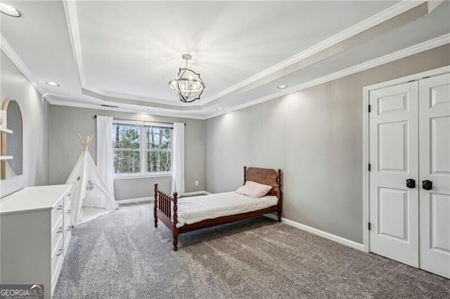 carpeted bedroom featuring a notable chandelier, crown molding, a closet, and a raised ceiling