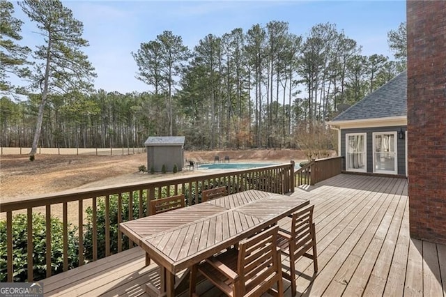 wooden terrace with a storage shed and a covered pool