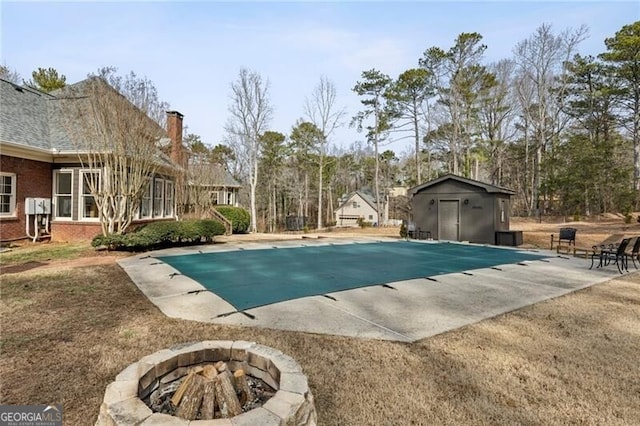 view of swimming pool featuring a patio, an outdoor structure, and an outdoor fire pit