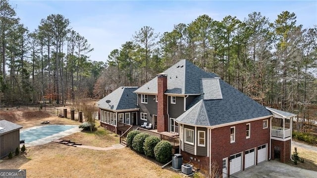 rear view of house with a swimming pool side deck, a garage, and central AC unit