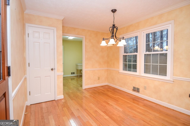 unfurnished room featuring crown molding, an inviting chandelier, and hardwood / wood-style floors