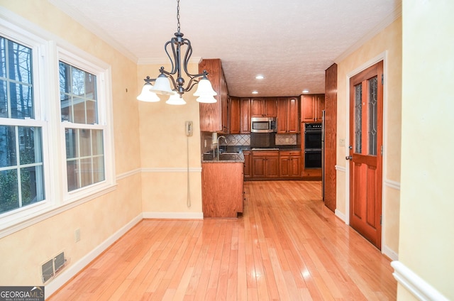 kitchen with an inviting chandelier, tasteful backsplash, pendant lighting, light hardwood / wood-style floors, and black appliances