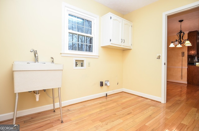 laundry room featuring sink, an inviting chandelier, hookup for a washing machine, cabinets, and light hardwood / wood-style floors