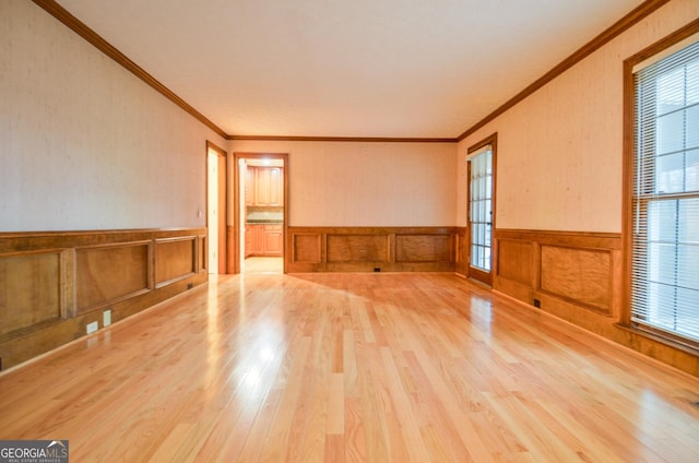 empty room with ornamental molding and light wood-type flooring