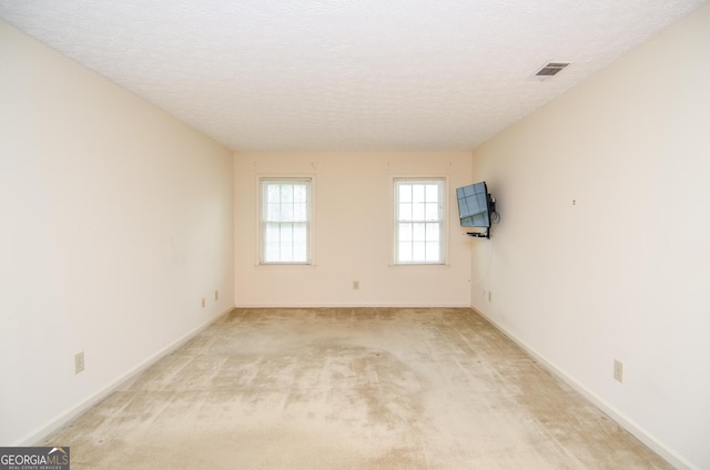 carpeted empty room with a textured ceiling