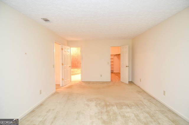 empty room with light colored carpet and a textured ceiling