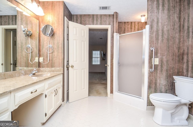 bathroom featuring vanity, toilet, a textured ceiling, and a shower with shower door