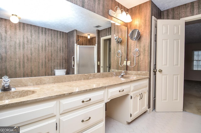 bathroom with tile patterned floors, toilet, a textured ceiling, vanity, and a shower with door