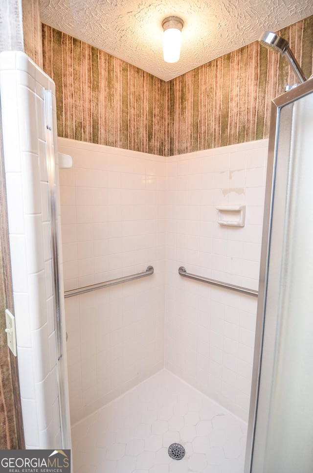 bathroom featuring a shower with door and a textured ceiling