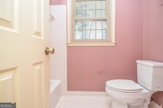 bathroom featuring a tub to relax in, toilet, and tile patterned flooring