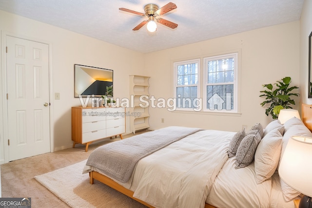 bedroom with ceiling fan, carpet flooring, and a textured ceiling