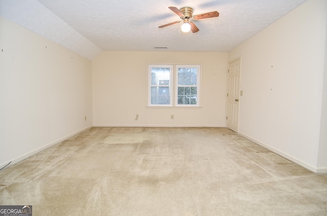 carpeted empty room featuring ceiling fan, lofted ceiling, and a textured ceiling