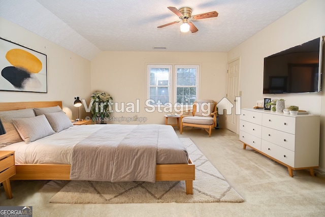 carpeted bedroom featuring ceiling fan, vaulted ceiling, and a textured ceiling