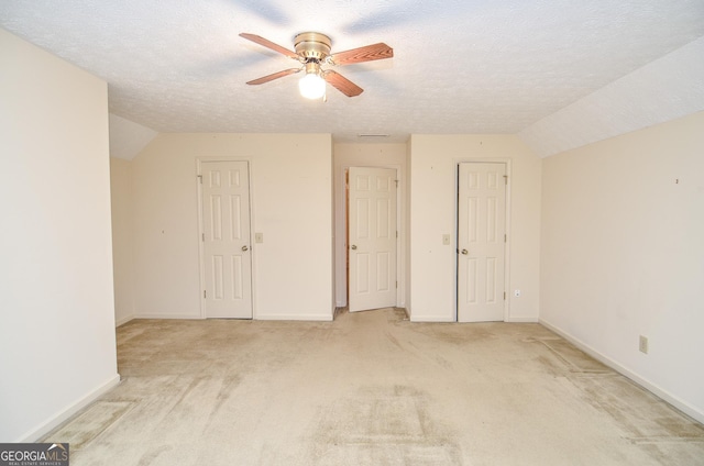 interior space with light carpet, ceiling fan, lofted ceiling, and a textured ceiling