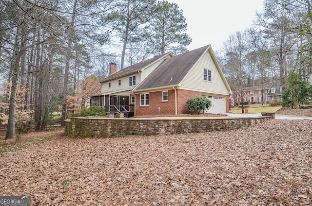 rear view of house with a garage and a sunroom