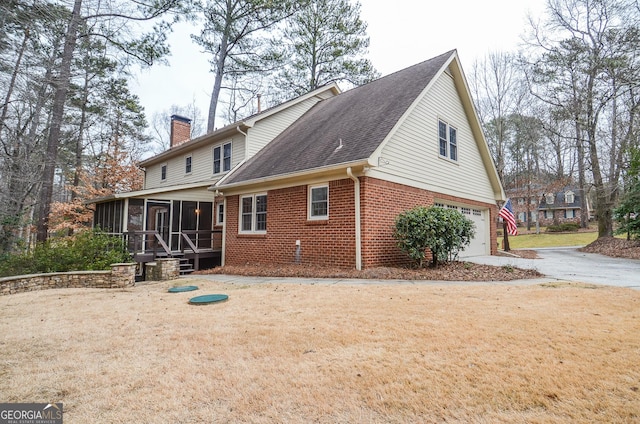 back of property with a garage and a sunroom