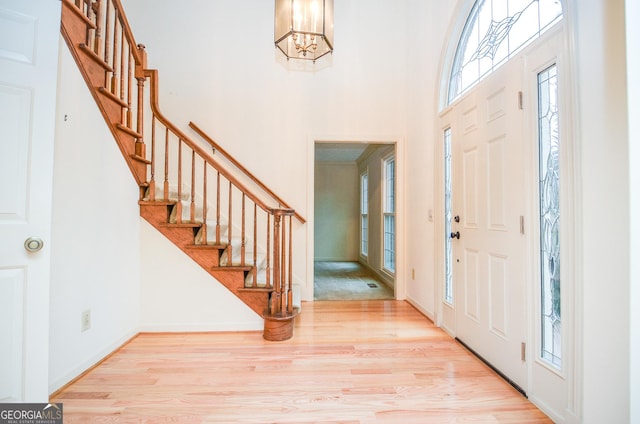 entryway featuring a high ceiling, a chandelier, and light hardwood / wood-style flooring