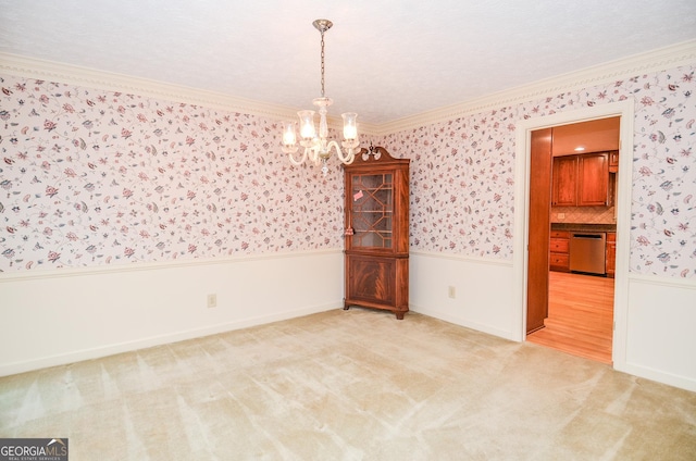 carpeted empty room with ornamental molding and a chandelier