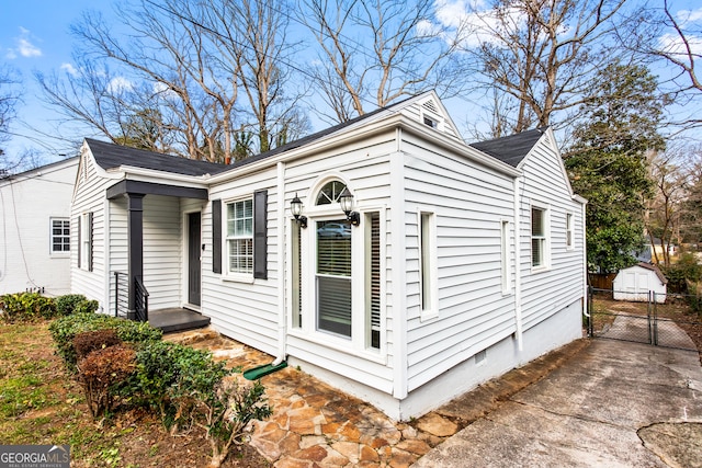 view of property exterior featuring crawl space, an outdoor structure, and fence