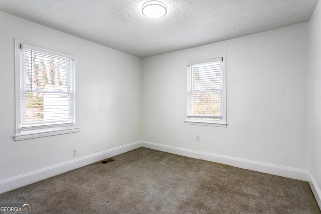 carpeted empty room with baseboards, visible vents, and a textured ceiling