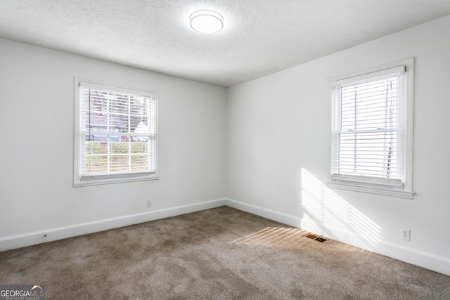 carpeted empty room featuring visible vents, baseboards, and a textured ceiling