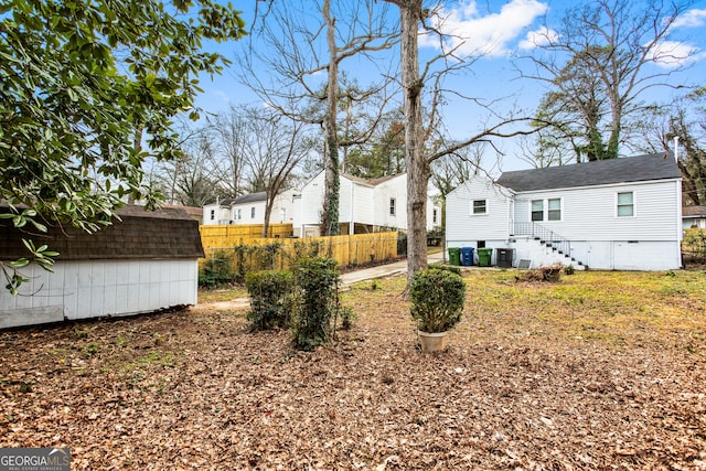 view of yard with an outbuilding, central air condition unit, a storage unit, fence, and a residential view