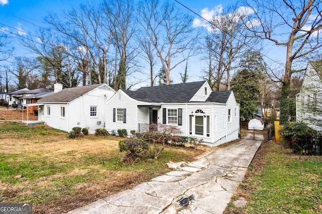 view of front of property featuring concrete driveway, a front lawn, roof with shingles, and a gate