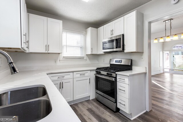 kitchen featuring white cabinetry, appliances with stainless steel finishes, a sink, and wood finished floors