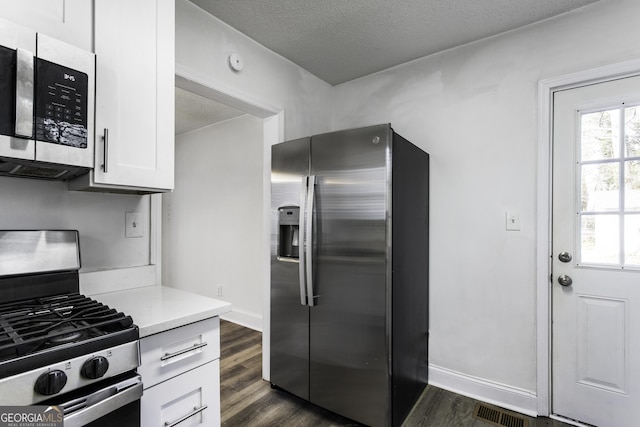 kitchen with visible vents, white cabinets, dark wood-style flooring, stainless steel appliances, and light countertops