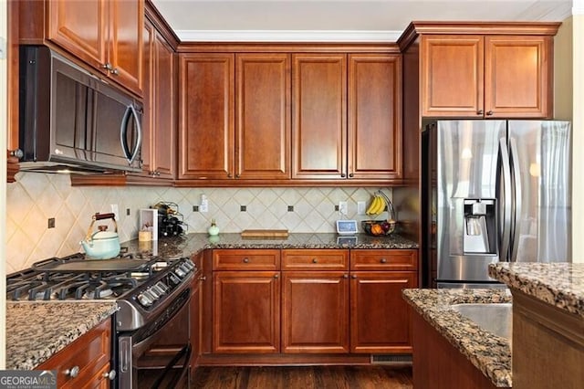 kitchen with backsplash, dark wood-type flooring, stainless steel appliances, and dark stone counters