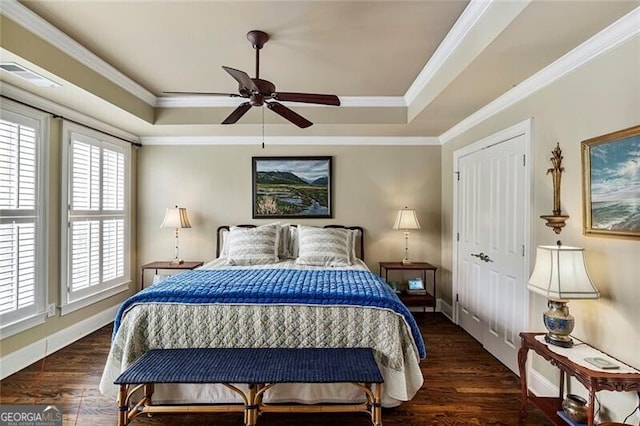 bedroom featuring crown molding, a tray ceiling, and dark wood-type flooring