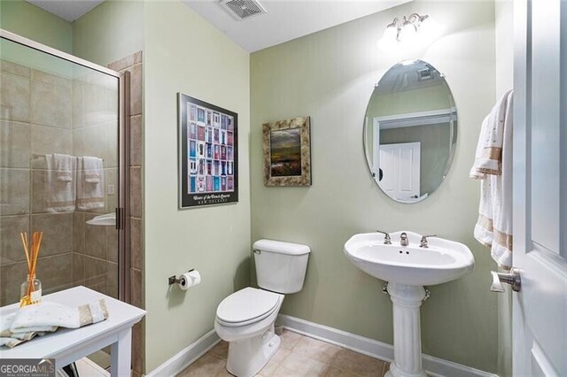 bathroom with toilet, tile patterned floors, and a shower with shower door