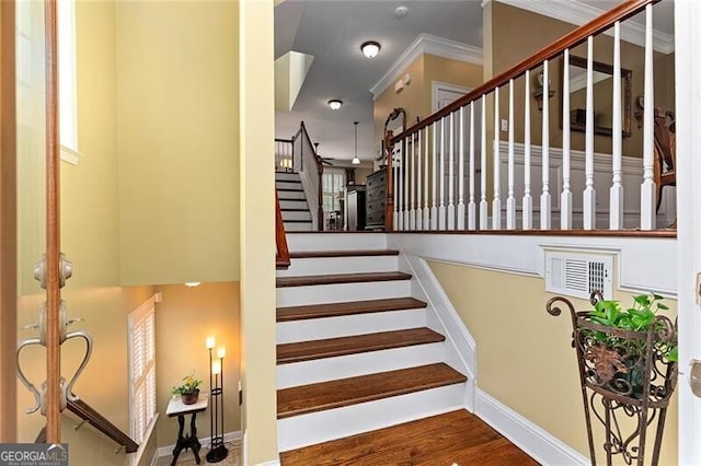 stairway with crown molding and wood-type flooring