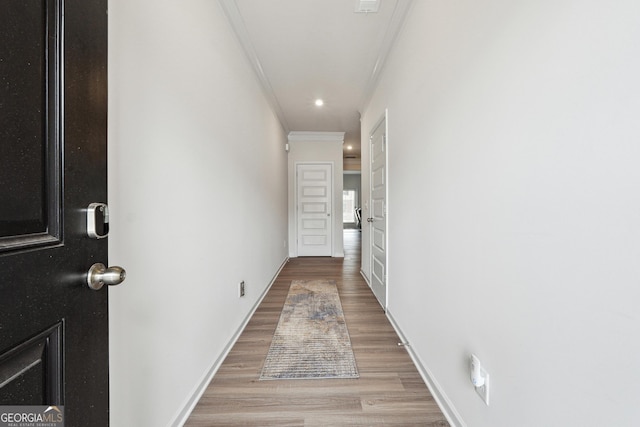 hall with ornamental molding and light hardwood / wood-style floors