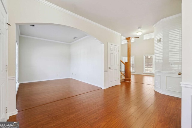 empty room featuring hardwood / wood-style floors, ornamental molding, and decorative columns