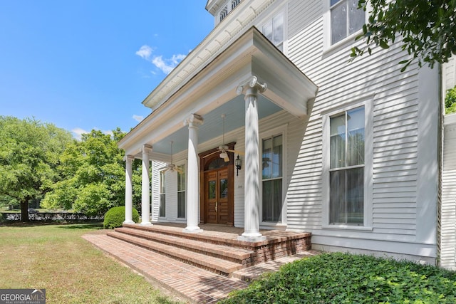 view of exterior entry with french doors, covered porch, and a lawn