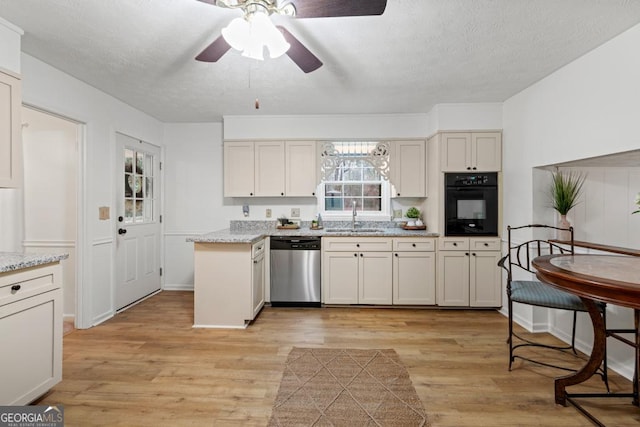 kitchen featuring sink, oven, stainless steel dishwasher, light hardwood / wood-style floors, and light stone counters