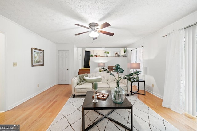 living room featuring ceiling fan, a textured ceiling, and light hardwood / wood-style floors