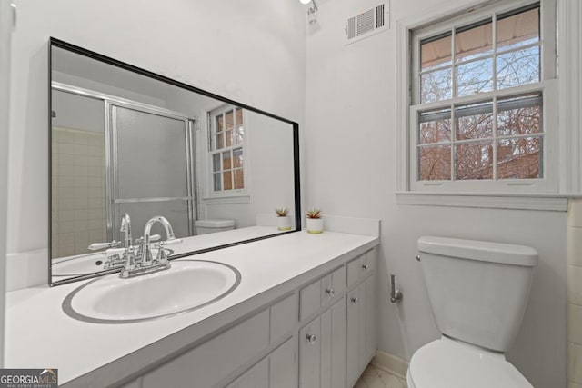 bathroom with a shower with door, vanity, and toilet