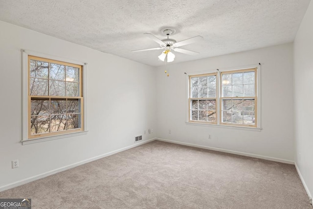 empty room featuring ceiling fan, carpet floors, and a textured ceiling