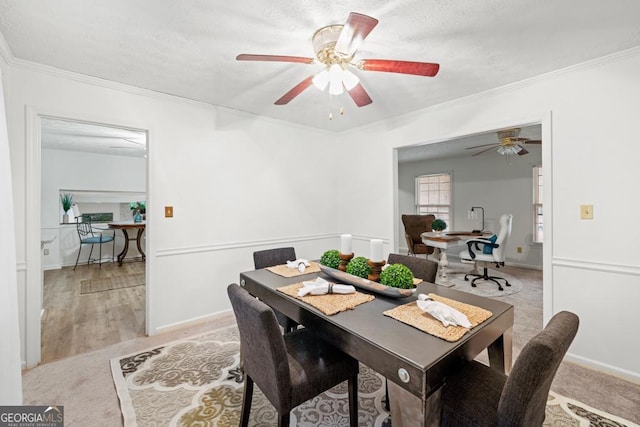 carpeted dining room featuring ornamental molding and ceiling fan