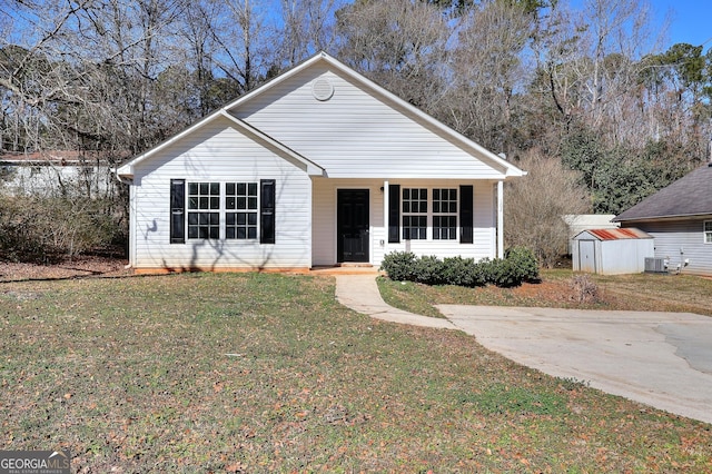 view of front of home with central AC, a front yard, and a shed