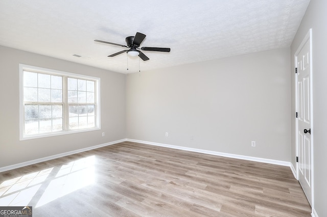 empty room featuring ceiling fan, light hardwood / wood-style floors, and a textured ceiling