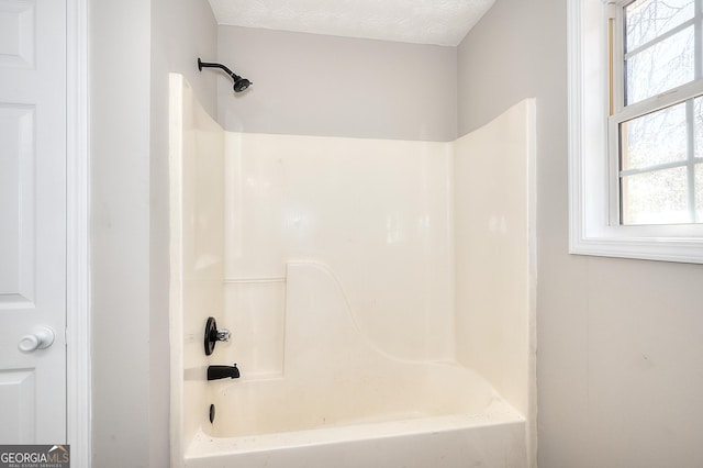 bathroom featuring bathtub / shower combination and a textured ceiling