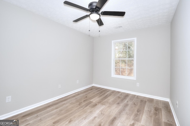 empty room with ceiling fan, light hardwood / wood-style floors, and a textured ceiling