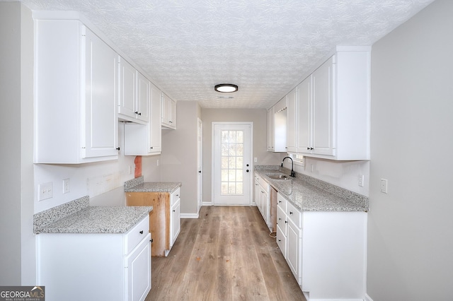 kitchen featuring white cabinetry, sink, a textured ceiling, and light hardwood / wood-style flooring